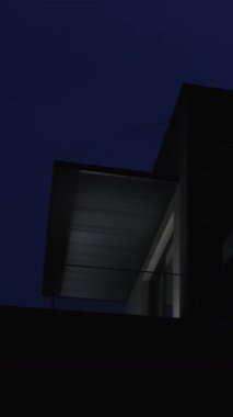 Geceleri aydınlatılan modern mimarinin çarpıcı bir görüntüsü, temiz çizgiler ve minimalist tasarım sergiliyor. Dikey video
