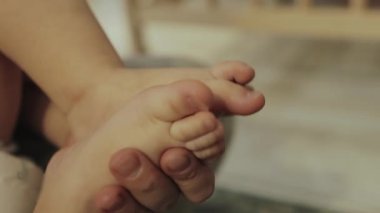 Anne bebeğin küçük ayaklarını tutuyor, yakın plan. Sevgi ve şefkat, aile ve annelik, sağlıklı çocuk ve ilgili orospu çocuğu görüntüleri.