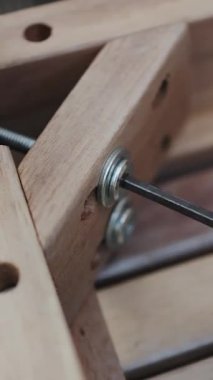 Dikey ekran: Ahşap mobilya parçaları titizlikle monte edilirken vidaları sıkılaştıran bir elin yakından görüntüsü. 4k