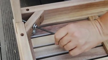 Tahta mobilyaları titizlikle monte ederken vidaları sıkılaştıran bir elin yakından görüntüsü. 4k