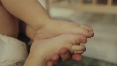 Sevecen ve nazik bir bakıcının tatlı bir bebeğe rahatlatıcı bir ayak masajı yaparken dokunuşunu yakalıyorum.