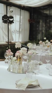 Zarif ve göz kamaştırıcı çiçek süslemeleri sergileyen çok güzel düzenlenmiş bir düğün masası. Dikey video