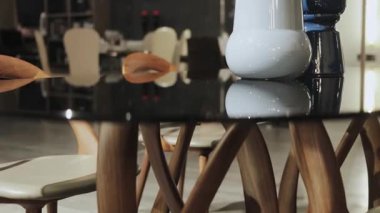 Modern tasarımın ahşap bacakları ve siyah cam yüzeyi olan bir karışımını sunan şık bir yemek masası..