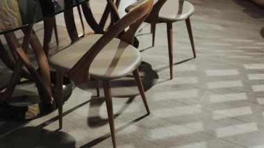 Modern sandalyelerin eşsiz bir şekilde tasarlandığı, gölgeli güzel bir oyun sergilediği zarif bir yemek seti.