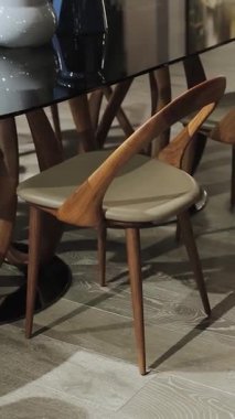 Bu zarif ve şık yemek alanında şık cam yemek masasının etrafına mükemmel bir şekilde yerleştirilmiş çağdaş sandalyeler yer alıyor. Dikey çekim. 