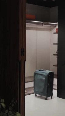 Modern bir iç mekanda gardıropta duran bir bavul, çağdaş modern tasarımın etkin bir şekilde sergilendiği minimalist bir ortam. Dikey video