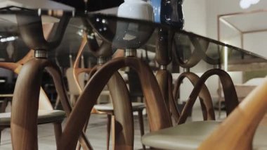Mükemmel ahşap bacaklara ve zarif dekoratif vazolara sahip parlak cam bir masa içeren modern bir yemek salonu.