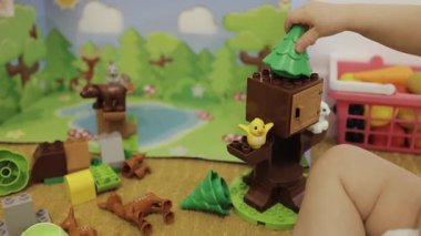 Bir çocuk neşeyle renkli blokları birleştiriyor, hayvanlarla dolu canlı bir ağaç sahnesi yaratıyor.