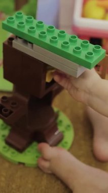 Dikey ekran: Çocuk odasında yerde otururken renkli yapı taşlarıyla oynuyor. Eller 4K 'ya yakın olsun.