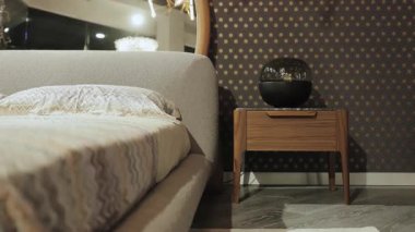 Zarif dekorlu, ahşap komodinli ve üzerinde lamba olan modern bir yatak odası. Yüksek kalite 4k görüntü