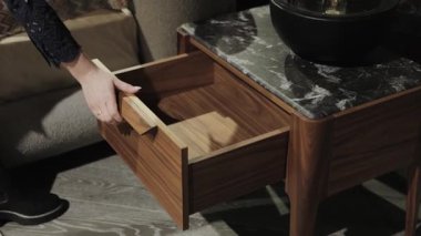 Bir kadının eli, modern bir komodinin çekmecesini kapatır. Modern Oturma Odası 'nda Zarif Çekmece Açılışı Görsel Bir Görsel Deneyim Oluşturur. Yüksek kalite 4k görüntü