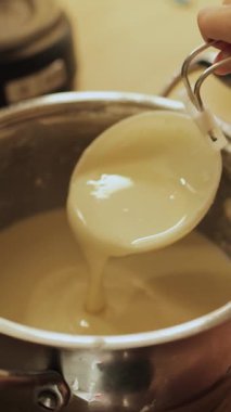 Küçük bir çocuk tencereden renkli bir sıvı dökerek neşeli ve neşeli bir yemek pişirme anını sergiliyor. Dikey çekim. - Evet. Yüksek kalite 4k görüntü