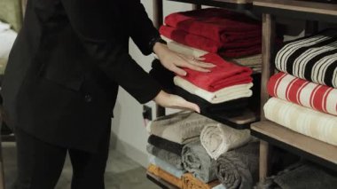 Bir kadın mağazadaki bir rafa havlu yerleştirir. Katlanmış havlular yığını. Uygun sunum ve tüketici cazibesi için perakende satış yerlerindeki raflarda havlu düzenlemek. Yüksek kalite 4k görüntü