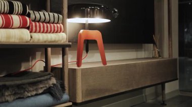 Çağdaş bir lamba, ev dekorasyonu için mükemmel olan şık tekstil ürünleriyle dolu rahat bir iç mekanı aydınlatır..