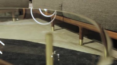 Tahta bacaklı bir kanepenin yakın çekimi. Cam kapaklı şık bir sehpa ve ev için ahşap taban. Yüksek kalite 4k görüntü