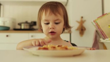Çocuk, annesinin ona kaseden verdiği yiyeceği yemek istemiyor. Parmağıyla başka bir şey istediğini işaret ediyor. Yüksek kalite 4k görüntü