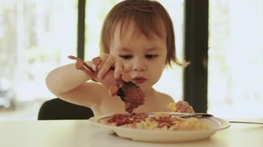 Bir çocuk, evdeki parlak bir oturma odasında yemek yerken lezzetli yemeklerden ve oyuncaklarından zevk alır ve oyuncak aslanlarını evde besler. Yüksek kalite 4k görüntü