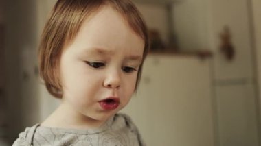 Neşeli bir çocuk, lezzetli bir aperatifin tadını çıkarıyor güzel stili olan bir mutfakta, tam zamanında yakalandı.