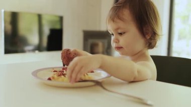 Mutlu küçük çocuk lezzetli bir spagetti kasesinin tadını çıkarıyor ve parlak bir odada en sevdiği oyuncağıyla oynuyor. Yüksek kalite 4k görüntü