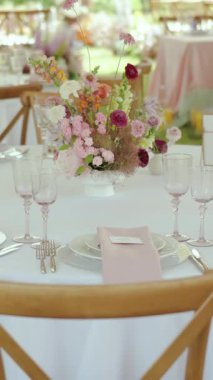 Dikey video. Masa dekorunda taze, canlı çiçekler, zarif bardaklar ve hoş pembe bir tema var. Düğün günü. Yüksek kaliteli FullHD görüntüler