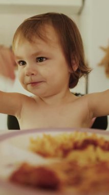 Neşeli bir çocuk rengarenk yiyeceklerle coşkulu bir şekilde meşgul olur, yemek saatlerinde zevk ve mutluluk gösterisi yapar.