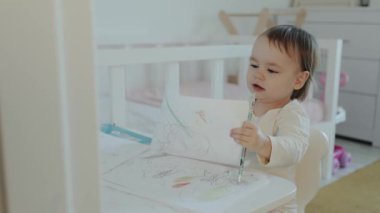 Neşeli, genç bir çocuk, yaratıcılık ve neşe saçan rahat ve parlak bir odadaki renklere derinden odaklanır.