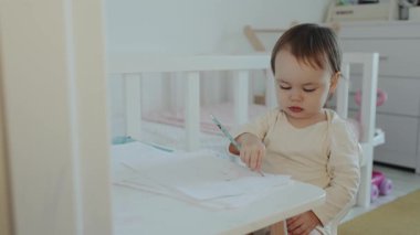 Genç bir çocuk, rahat bir çocuk odası ortamında çizim ve boyama yaparak yaratıcılıklarını neşeyle keşfediyor.