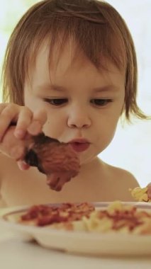 Dikey çekim. 3 yaşındaki bir çocuk, evdeki parlak bir oturma odasında yemek yerken lezzetli bir yemeğin tadını çıkarıyor, pelüş aslan oyuncağını evde oynuyor ve besliyor. Yüksek kalite 4k görüntü