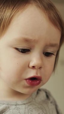 Dikey video. Sevimli çocuk, neşeli ve neşeli bir mutfak ortamında lezzetli bir yemeğin tadını çıkartıyor. Omlet yiyen üç yaşında bir kız. Yüksek kalite 4k görüntü