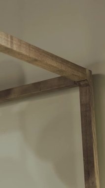 Kanopili ahşap yatak. Ahşap mobilya elementine yakın çekim. Modern bir yatak odasında yatak duvara dayanır. Dikey video. Yüksek kalite 4k görüntü