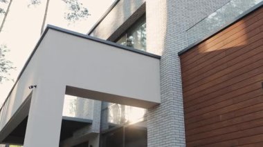 Çarpıcı, çağdaş bir ev, beyaz, doğal ahşap ve berrak camlarla harmanlanır ve sakin doğal bir manzaraya yerleştirilir. Yüksek kalite 4k görüntü