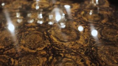 Karmaşık desenleri ve ışığın yumuşak yansımaları olan mermer bir masanın yakın çekimi. Kamera düzgün hareket eder ve masanın üzerindeki mermerin dokusunu gösterir. Yüksek kalite 4k görüntü