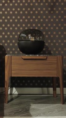 Ahşap komodin. Zarif dekorlu modern yatak odası, üzerinde ahşap komodin ve lamba duruyor. Dikey video. Yüksek kalite 4k görüntü