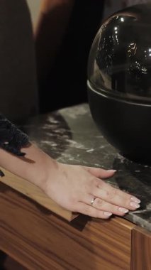 Dikey ekran: Bir kadın eli nazikçe komodinin üzerinden geçer, ahşap, mermer. Ağır çekim. Güzel hazırlanmış dekoratif bir nesneyi gösteriyor. Ağır çekim. Yüksek kalite 4k görüntü