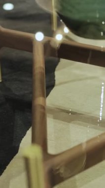 Yakın plan, tahta masa bacakları. Ahşap bacakları ve güzel cam kapağı olan zarif ve modern kahve masası. Yakın plan. Modern oturma odası iç tasarımı. Kamera sorunsuz hareket ediyor. Dikey video. Yüksek kalite