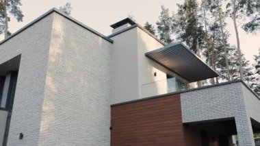 Modern mimari tasarım camdan balkonlu, çatılı arka planda çamlar olan özel bir ev. Modern mimari. Yüksek kalite 4k görüntü