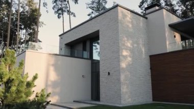 İki katlı modern ev zarif ahşap ve taş elementler, fayanslar ve tuğlaları birleştiriyor. Ağaçlı, manzaralı bir avlunun yanında. Yüksek kalite 4k görüntü