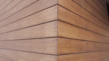 Kamera, ahşabı taklit eden ön cephedeki fayanslarla kaplı bir evin duvarında yakın çekim yapar. Tuğla dokusu. Evin dışından. Yüksek kalite 4k görüntü