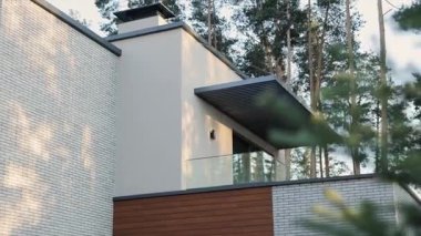 Uzun ağaçlarla çevrili gösterişli, yenilikçi mimari ve stil içeren gösterişli modern bir ev tasarımı.