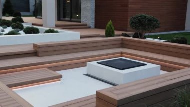 Teras, ahşap döşeme ve şömine modern evin yanında. Barbekü alanının yanında ışıklandırma olan açık hava terası. Açık verandada şömine var. Yüksek kalite 4k görüntü