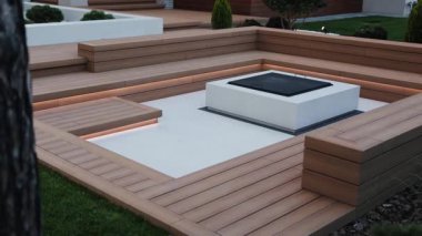 Çağdaş ateş çukurlu modern veranda, LED ışıklandırmalı ahşap teras ve modern yakındaki ahşap banklar. Barbekü alanının yakınında ışıklandırma olan bir avlu. Yüksek kalite 4k görüntü