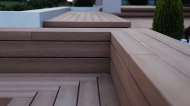 Akşam avlunun yanındaki ahşap teras ve evin yanındaki bahçe. Aydınlatılmış ahşap terası olan akşam rahatlama alanı. Tahta bank. Ağır çekim. Yüksek kalite 4k görüntü