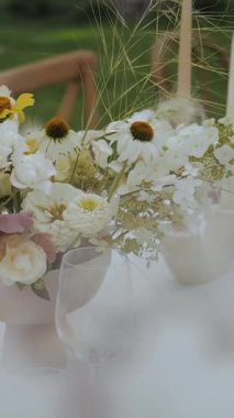 Beyaz, sarı ve beyaz çiçekli bir vazo. Düğün masası, kutlama. Bir düğünde açık hava çiçek aranjmanı. Yüksek kalite 4k görüntü