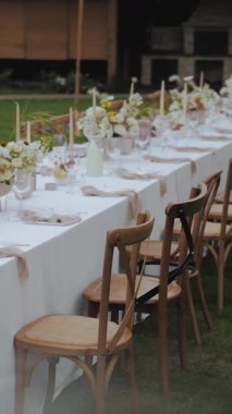 Dışarıda zarif bir şekilde düzenlenmiş uzun masa seti. Güzel düğünler ya da sosyal toplantılar için ideal. Yüksek kalite 4k görüntü