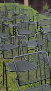 Çimlerin üzerindeki bir parkta düzenlenen düğün töreninde boş siyah sandalyelerin yakın çekimi, arka planda yeşil çimenler, yavaş çekim. Yüksek kalite 4k görüntü