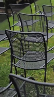 Dikey video. Bir düğün töreninde arka tarafta siyah boş sandalyeler, çimenlerin üzerinde güzel bir hava, yakın plan, arka planda yeşil çimenler. Yüksek kalite 4k görüntü