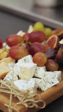 Dikey video. Camembert peyniri, crostini, incir, üzüm, bal ve fındıklı peynir tabağı. Tahtadaki meyveler. Şarap seti. Yüksek kaliteli 4K video. Yüksek kalite 4k görüntü