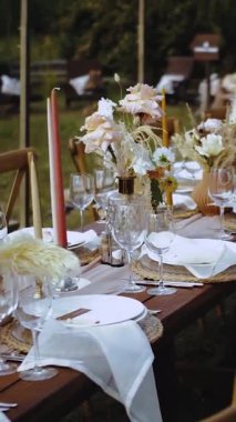 Dikey video. Düğün dekoru, şenlikli yemek ya da parti, kapalı alan resepsiyonu. Boho tarzı açık hava düğünü, tabaklar ve bardaklar, insan ya da yemek yok, ağır çekim. Dikey video. Yüksek kalite 4k görüntü