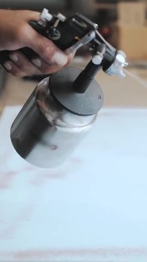 Dikey video. Döşeme mobilyası üreten bir fabrikada çalışan bir işçi. Sprey tabanca kullanan bir adam. Döşeme mobilyası ve köpük yapıştırma işlemi. Yüksek kalite 4k görüntü