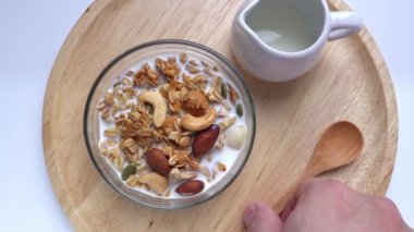 Mısır gevreği, tahtadan yapılmış sütlü fındık. Kadın tatlı vegan gevrek kasesi yiyor. Sağlıklı kahvaltı. 4k video